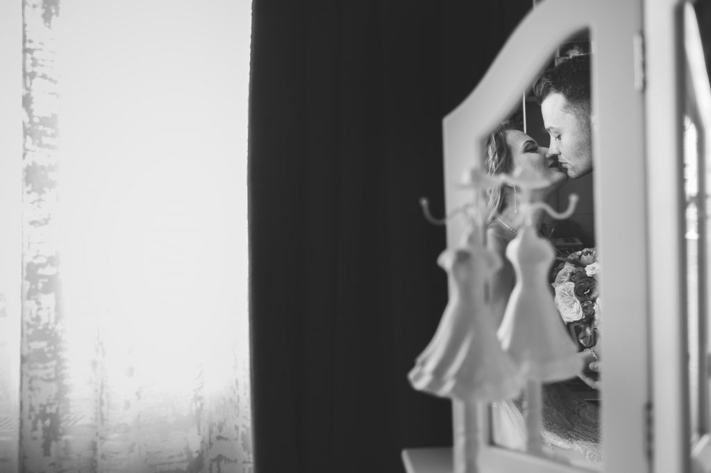 mire și mireasă, care se sărută, surprinși într-o oglindă