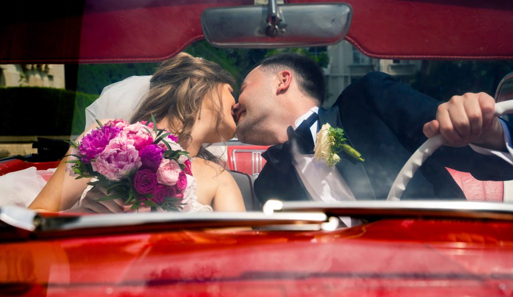 mire ș mireasă la ședința foto de nuntă, într-o mașină roșie, vintage, decapotabilă